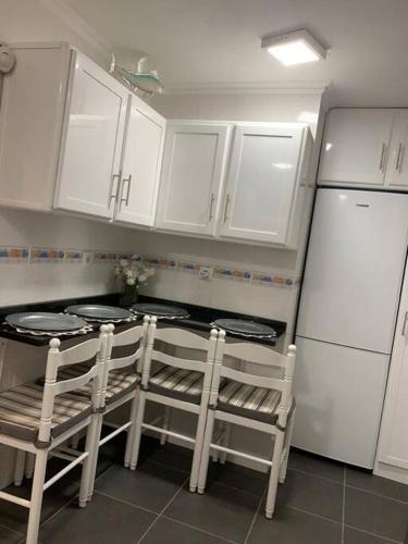 a kitchen with white cabinets and a stove and two chairs at Cozy chalet with ocean view in Seixal