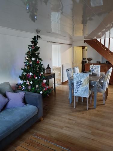 un arbre de Noël dans un salon avec un canapé bleu dans l'établissement Les petits cailloux, à Saint-Médard-de-Mussidan
