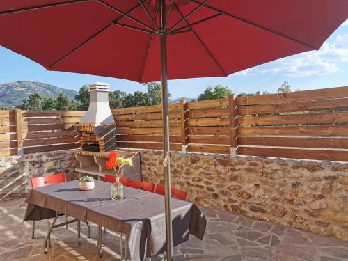 a table with a red umbrella on a patio at CASITAS PINILLA DEL VALLE in Pinilla del Valle