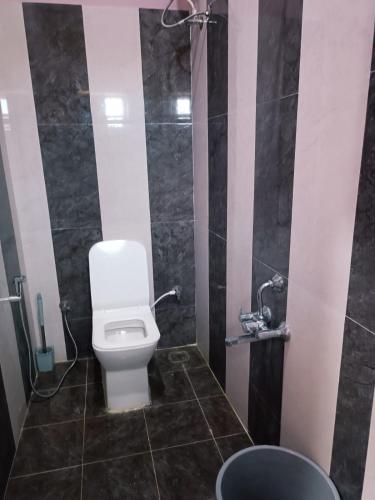 a bathroom with a white toilet and a shower at Alif Serviced (Hotel) Apartments in Tambaram