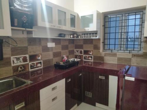 a kitchen with white cabinets and brown tile on the wall at Alif Serviced (Hotel) Apartments in Tambaram