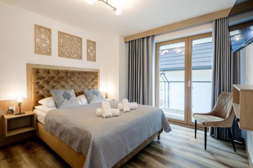 een slaapkamer met een groot bed en 2 witte handdoeken bij Tatra View 2 Apartamenty Księżycowe SPA in Zakopane