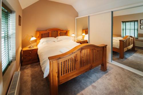 1 dormitorio con 1 cama grande y espejo grande en Delphi Lodge Cottages, en Leenaun