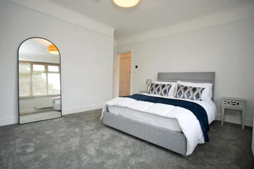 a white bedroom with a large bed and a mirror at A Piece of Seaside Serenity on the Sandbanks Peninsula in Sandbanks