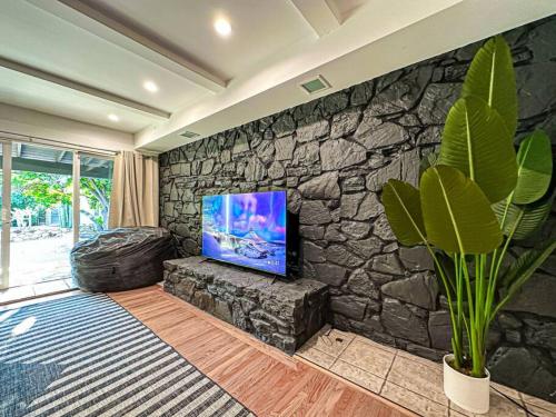 Il comprend un salon doté d'un mur en pierre et d'une télévision à écran plat. dans l'établissement Relaxing 6 BR Oasis with Pool - Lou1, à Los Angeles