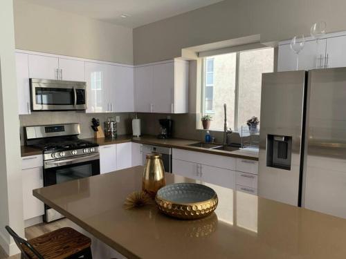 Capacious house in Mid City - CR3-WIN في لوس أنجلوس: مطبخ مع دواليب بيضاء وطاولة مع ثلاجة معدنية
