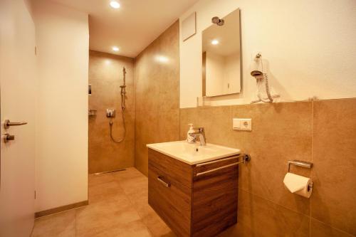 een badkamer met een wastafel en een douche met een spiegel bij Ferienwohnung Legau in Legau
