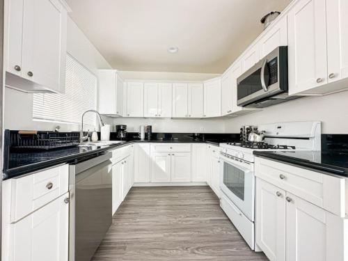 una cocina blanca con armarios blancos y encimeras negras en Cozy 3BR Oasis for Your Next Adventure in LA - WO en Los Ángeles