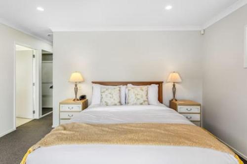 una camera da letto con un grande letto con due comodini di Opal of Orewa with pool, spa and ocean views a Orewa