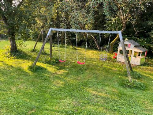 a swing set in a yard with a dog house at Gästehaus Grünberger in Hutthurm