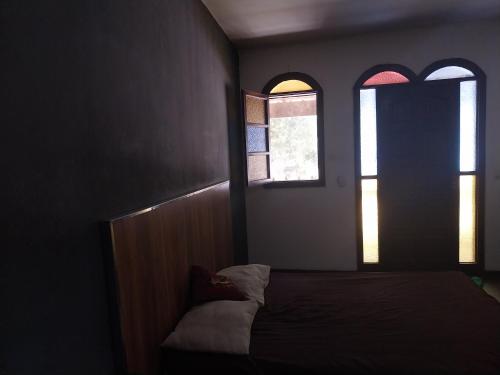 a bedroom with a bed and two windows at Casa confortável in Niterói