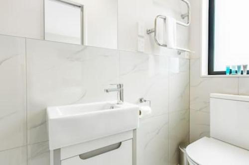 a white bathroom with a sink and a toilet at Urban Pulse Townhouse with parking in Auckland