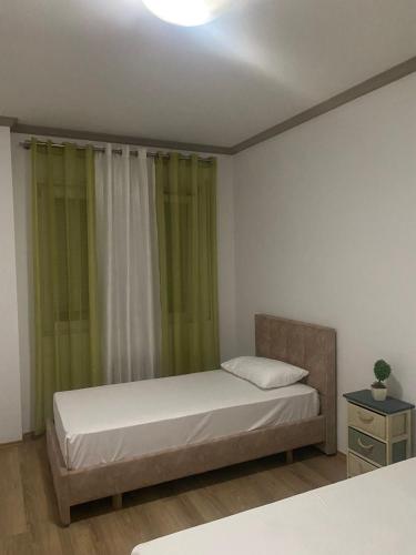 een slaapkamer met een bed met groene gordijnen bij Emma & Ella Apartment in Tirana
