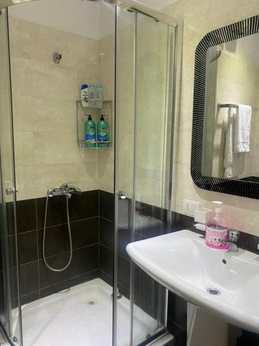 een badkamer met een glazen douche en een wastafel bij Emma & Ella Apartment in Tirana