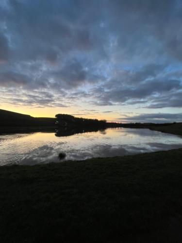 a body of water with the sun setting in the background at East Learmouth Lakeside Lodges in Cornhill-on-tweed