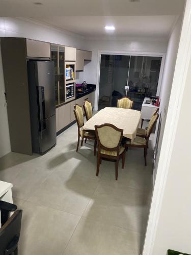 uma cozinha com uma mesa e cadeiras e um frigorífico em Suíte Master em Itajaí