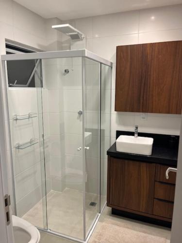 a bathroom with a glass shower and a sink at Apartamento São Francisco - Praia do Gravatá - Beto Carrero World in Navegantes