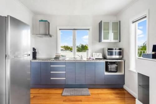 a kitchen with a sink and a refrigerator at Top-Floor Three-Bedroom Close to WestCity in Auckland
