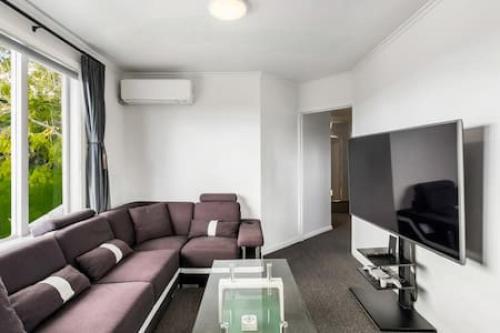 a living room with a couch and a flat screen tv at Top-Floor Three-Bedroom Close to WestCity in Auckland
