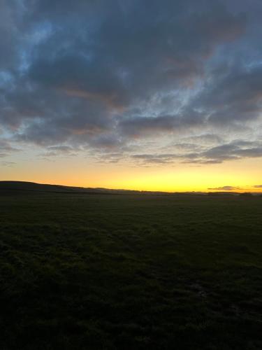 an open field with the sunset in the background at East Learmouth Lakeside Lodges - Larch Lodge in Cornhill-on-tweed