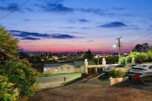 a view of a house with cars parked in a parking lot at Top-Floor Three-Bedroom Close to WestCity in Auckland