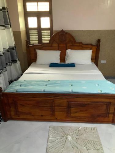 a bedroom with a wooden bed with a blue mattress at Zebra House Stonetown in Ngambo