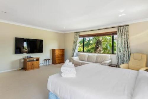 a bedroom with a bed and a couch and a television at Northpark Getaway with patio area in Auckland
