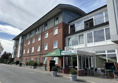 a large brick building with tables and chairs in front of it at Nordseehotel Wilhelmshaven in Wilhelmshaven