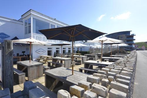 une rangée de tables avec parasols devant un bâtiment dans l'établissement Westpoint Dog Friendly Apartments, à West Bay