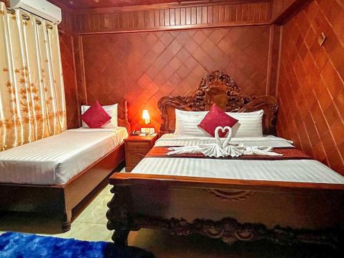 a bedroom with two beds with red pillows at HONG PEP HOTEL in Battambang