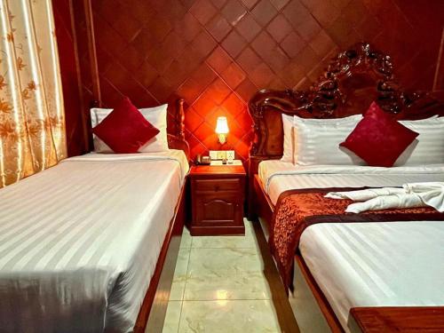 a room with two beds and a lamp on a table at HONG PEP HOTEL in Battambang