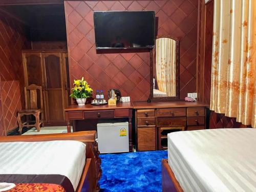 a bedroom with two beds and a television on a wall at HONG PEP HOTEL in Battambang