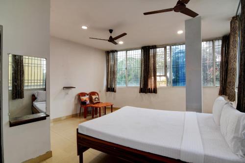 um quarto com uma cama branca e algumas janelas em OYO Hotel Lake View em Ranchi
