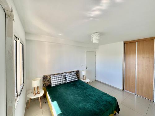 ein Schlafzimmer mit einem grünen Bett in einem weißen Zimmer in der Unterkunft T3 agréable au Gosier à proximité de la plage in Le Gosier