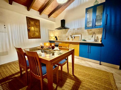 a kitchen with a wooden table and blue cabinets at Casa Rural “Los Campos” in Almogía