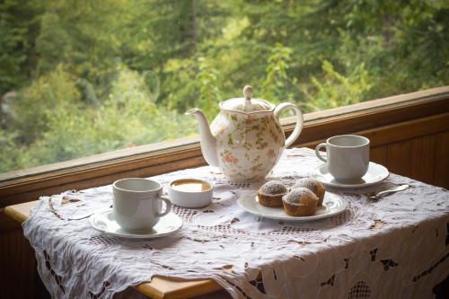 a table with a tea pot and cups and pastries at Hotel Las Cascadas in La Cumbrecita