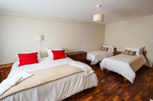 a bedroom with two beds with white and red pillows at Hotel Las Cascadas in La Cumbrecita