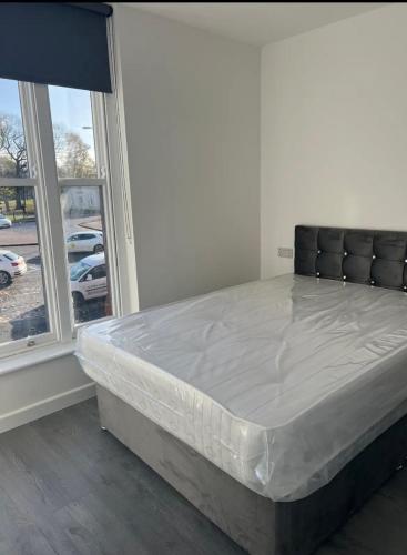 a bed sitting in a room next to a window at ASM London Road Studio Apartments in Leicester