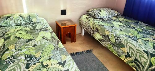 una camera con due letti e un comodino con tavolo di Moonsong Accommodation & Camping a Plettenberg Bay