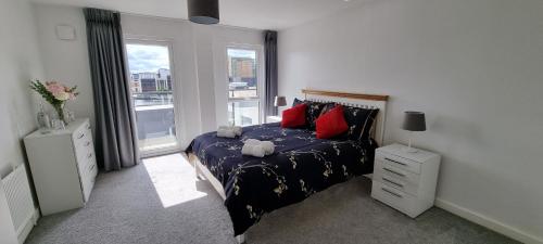 a bedroom with a bed with red pillows and a window at Room in City Centre Penthouse Apartment in Belfast