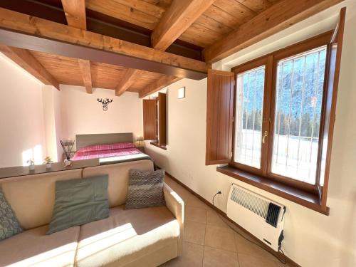 a room with a bed and a couch and windows at Affittimoderni Ponte di Legno Ski - PDL23 in Ponte di Legno