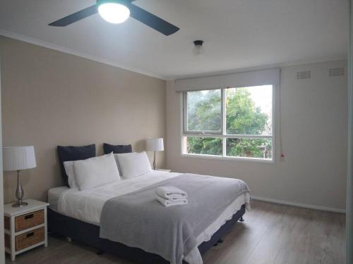 Un dormitorio con una cama con ventilador de techo. en Happy Spacious Home nr Canberra Hospital, en Harman