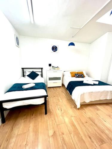 2 łóżka w białym pokoju z drewnianą podłogą w obiekcie Brilliant One Bedroom Flat in London w Londynie