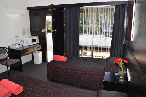 a living room with a couch and a desk and window at Warwick Motor Inn in Warwick