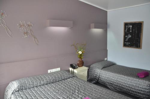 a bedroom with two beds and a vase of flowers at Warwick Motor Inn in Warwick