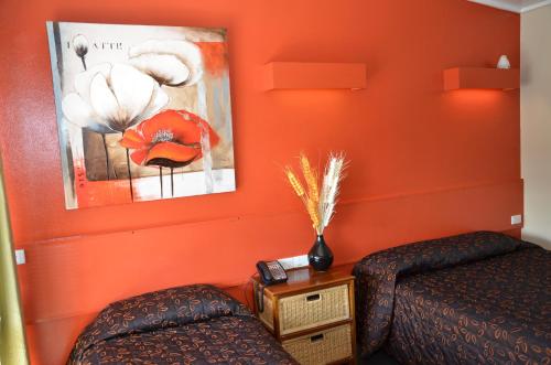 a bedroom with orange walls and a bed and a table at Warwick Motor Inn in Warwick
