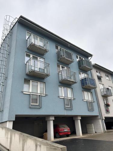 un edificio azul con balcones y un coche rojo en Cozy Studio in neighbourhood with Prague, en Beroun