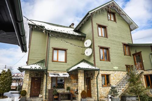 a large green house with a clock on it at Zatyshok nad Prutom in Bukovel