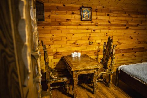 a table and chairs in a room with a wooden wall at Zatyshok nad Prutom in Bukovel