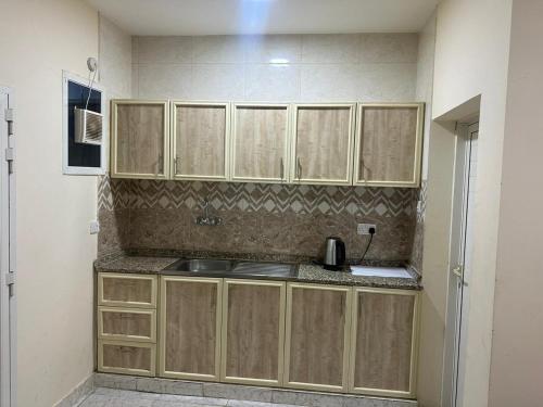 una cocina con armarios de madera y fregadero en luule, en Al Ain